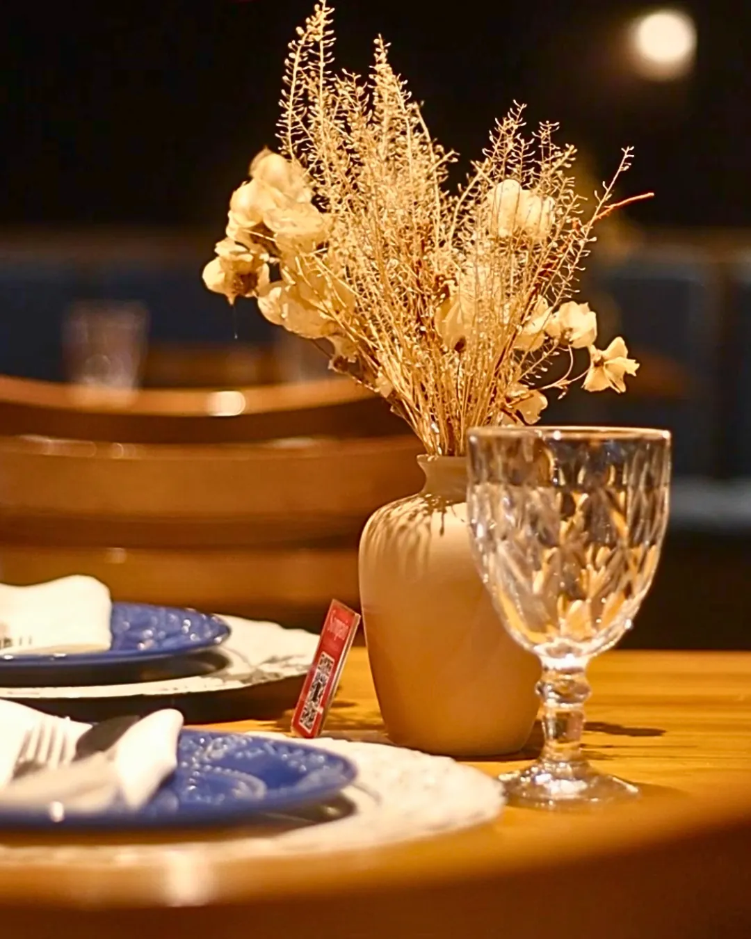 Detalhe da mesa posta com taça e flores secas